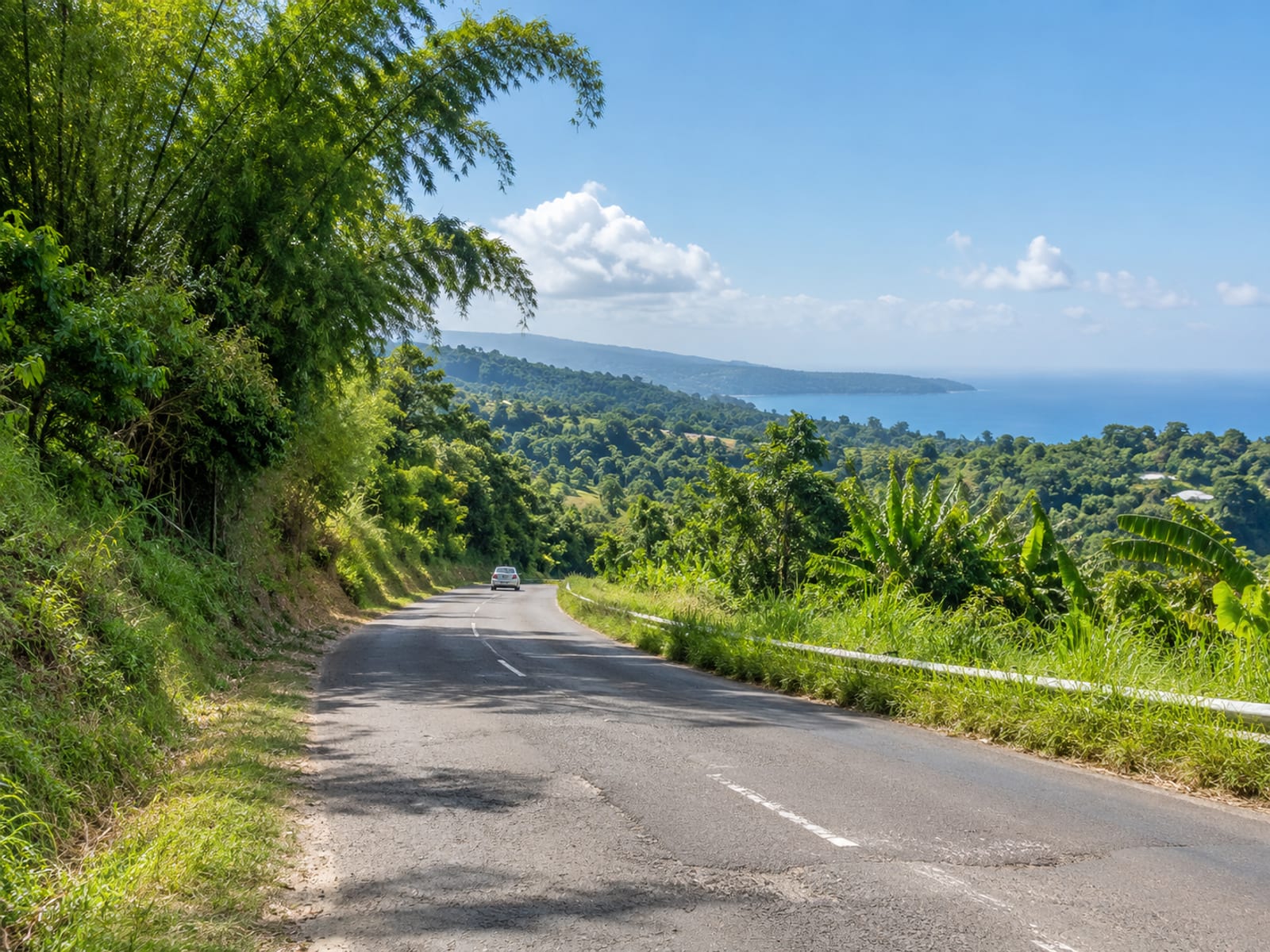Quiet country road winding through green hills with a very small plain car far in the distance