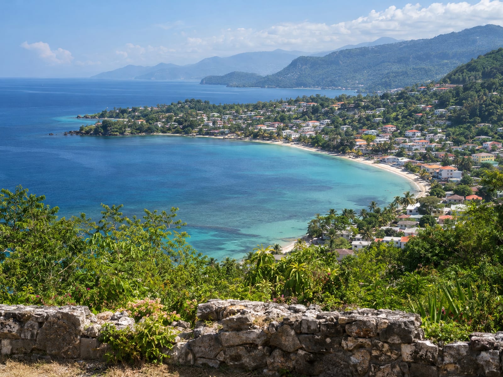 Wide hillside view across a curved bay with a small town along the shore and distant headlands.