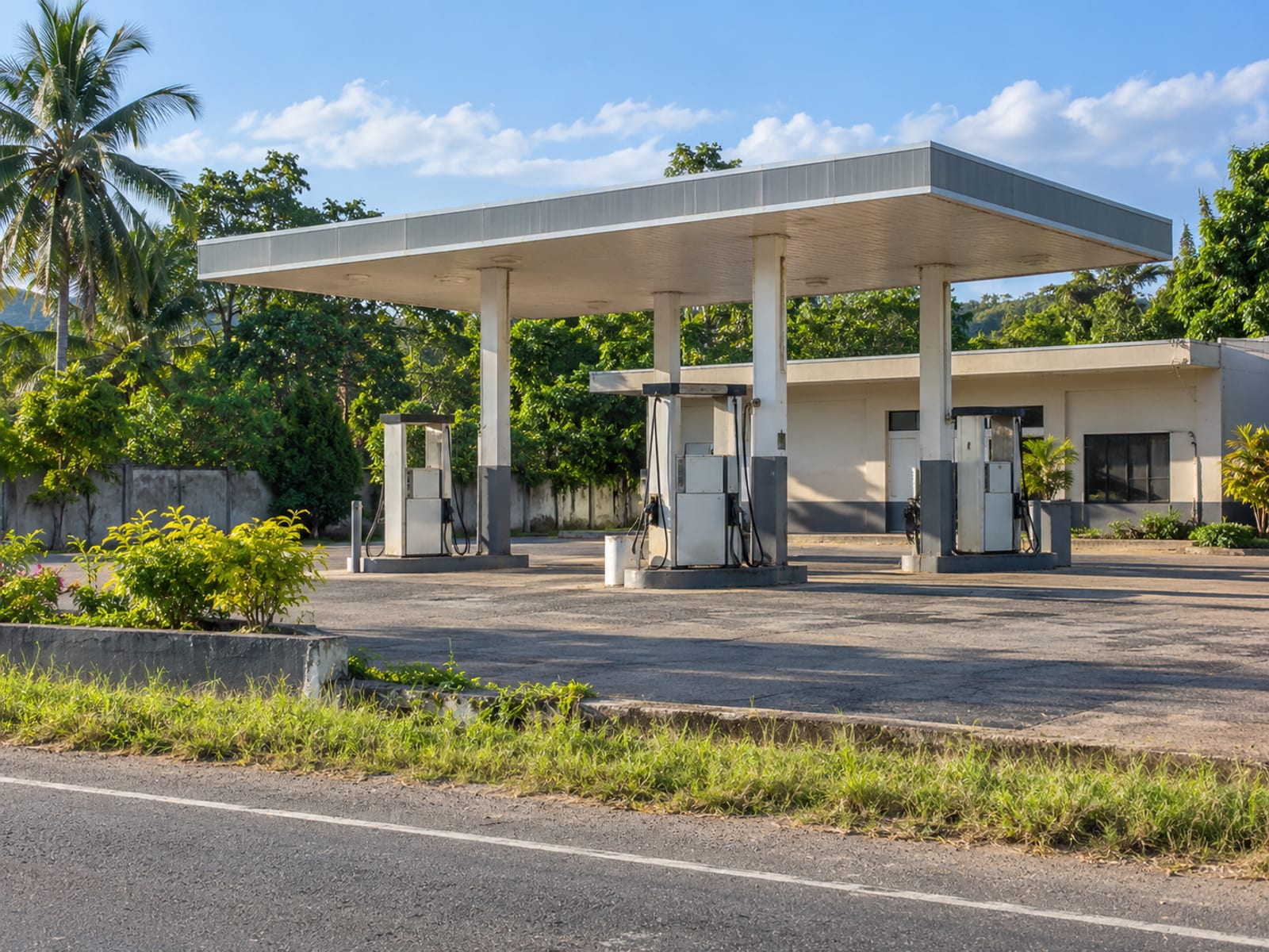 Plain fuel station forecourt with unbranded pumps seen across the road on a quiet afternoon