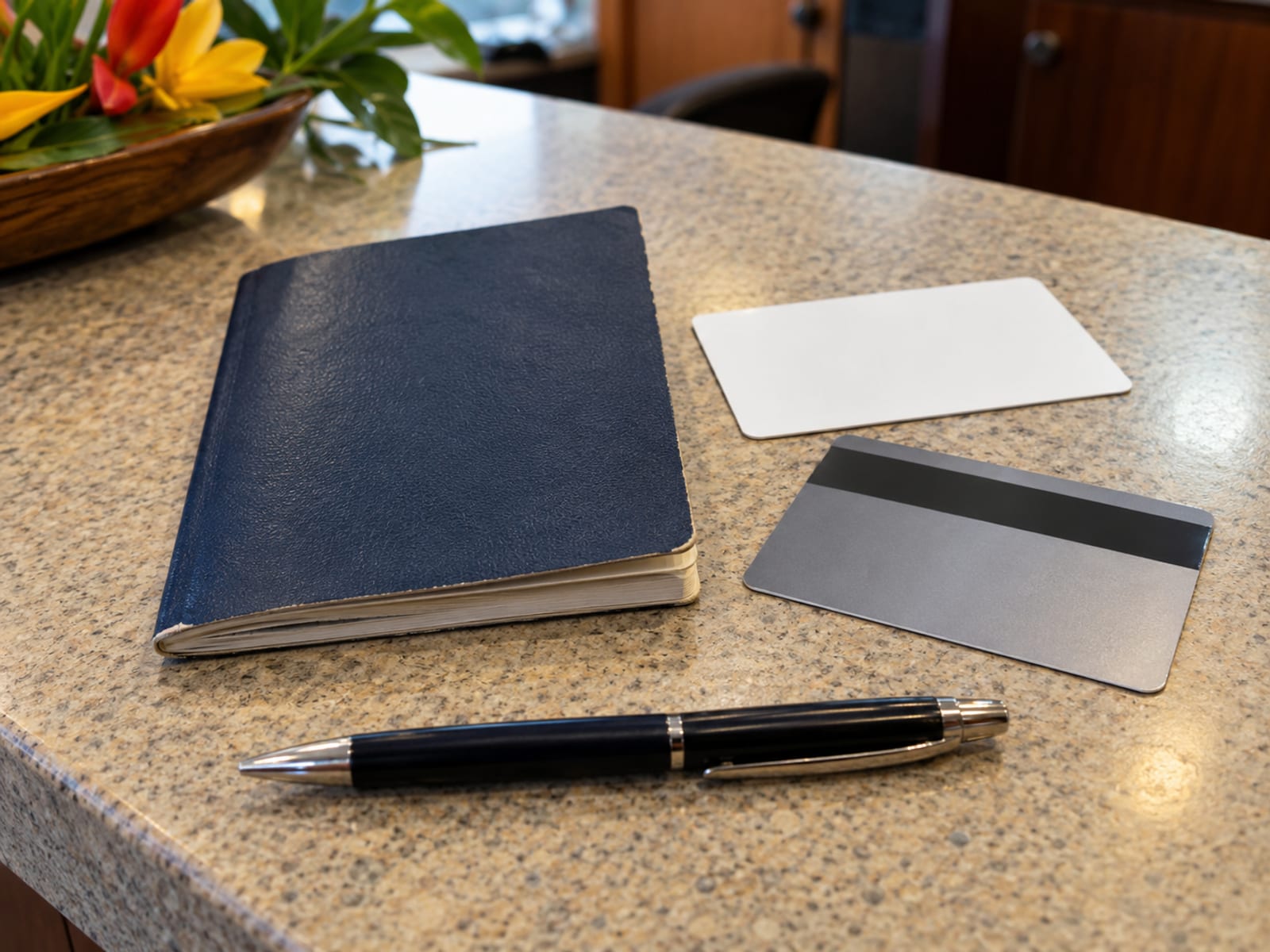 Closed passport, a blank plastic card and a payment card face down on a counter with a pen