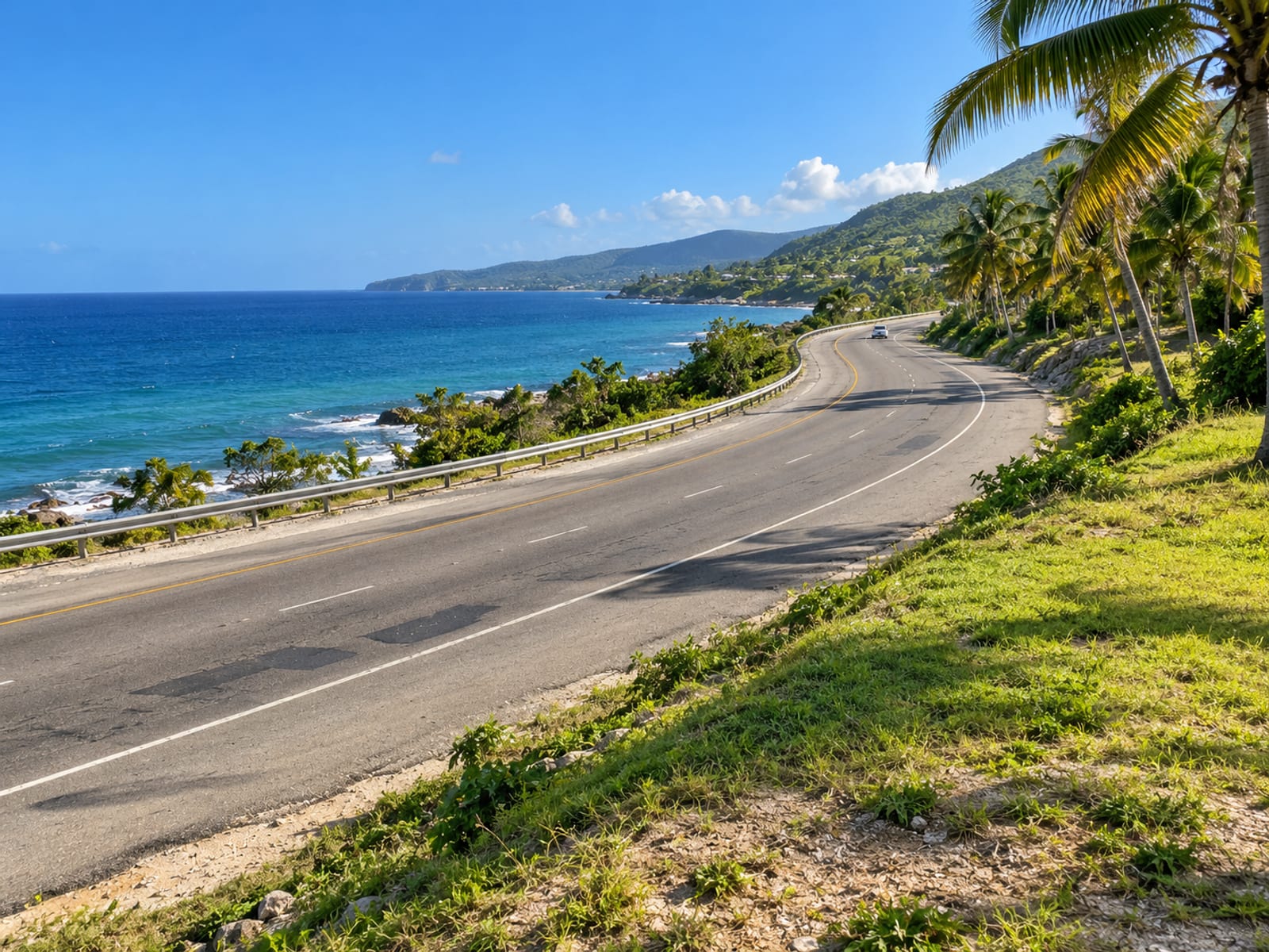Wide coastal highway curve beside the sea with open road and light holiday traffic far away