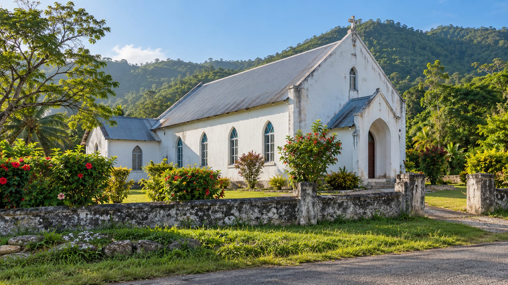 Small white painted country church with a pitched roof on a green hillside, seen from the road, no signs