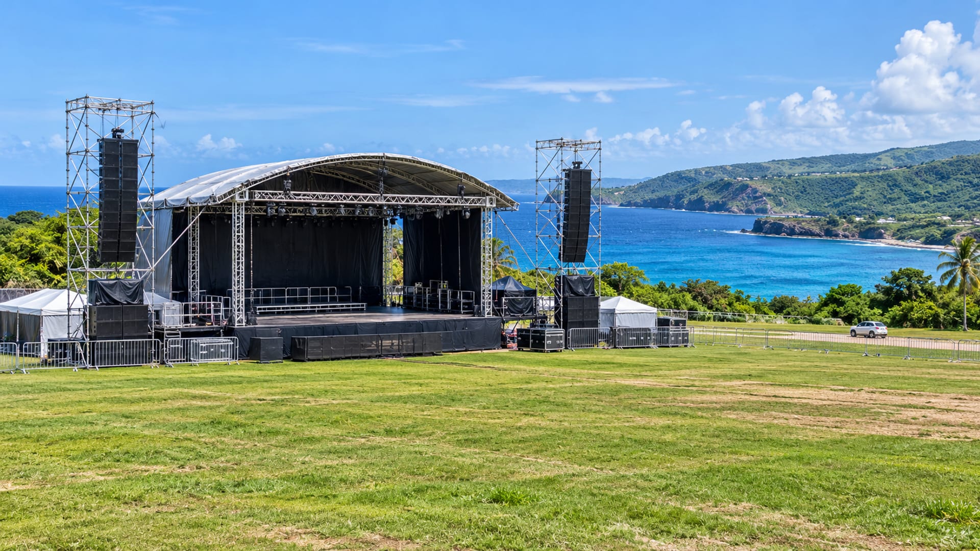 Wide view of an empty bare stage frame and a grass field beside the coast before an event