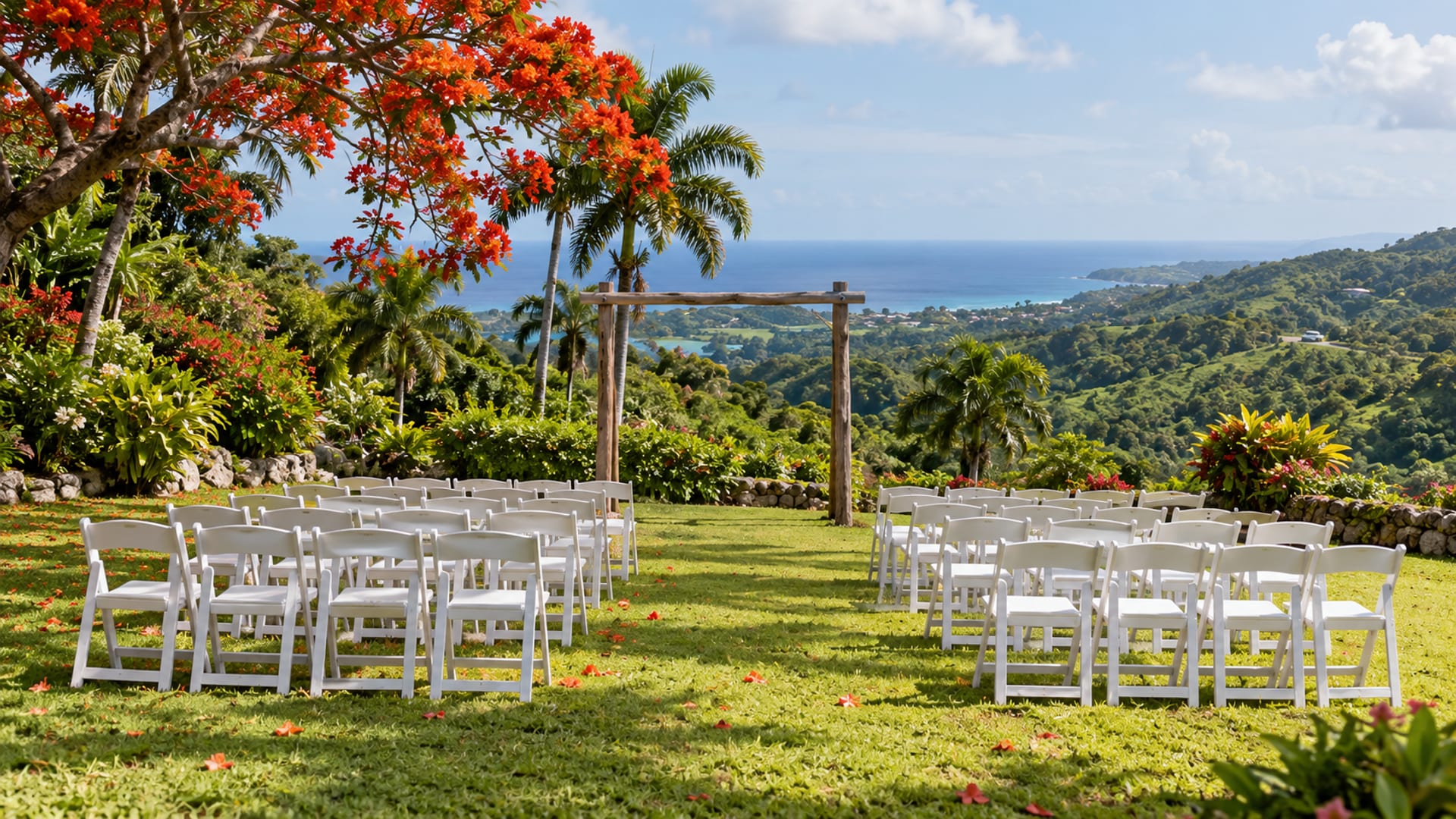Wide view of an empty lawn set with rows of white chairs facing a wooden arch, with flowering trees, hills and a strip of sea beyond