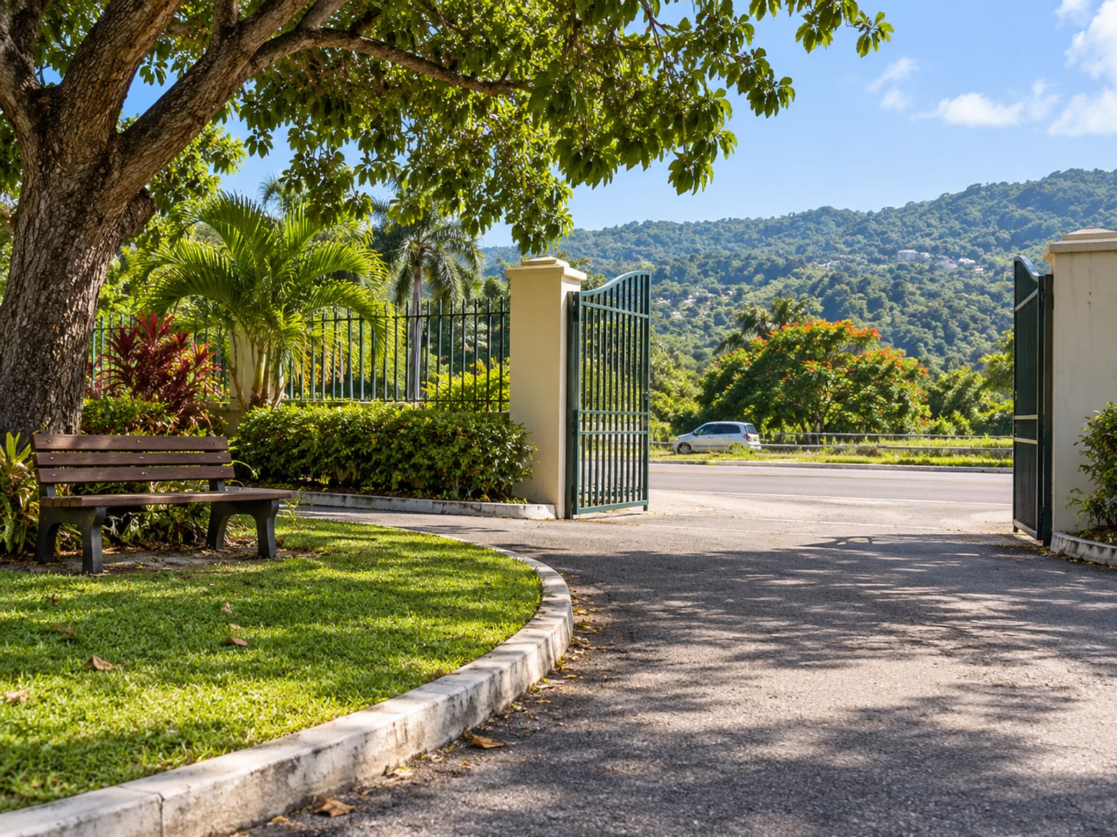 Open pedestrian gate beside a curved driveway with a wooden bench under a shade tree