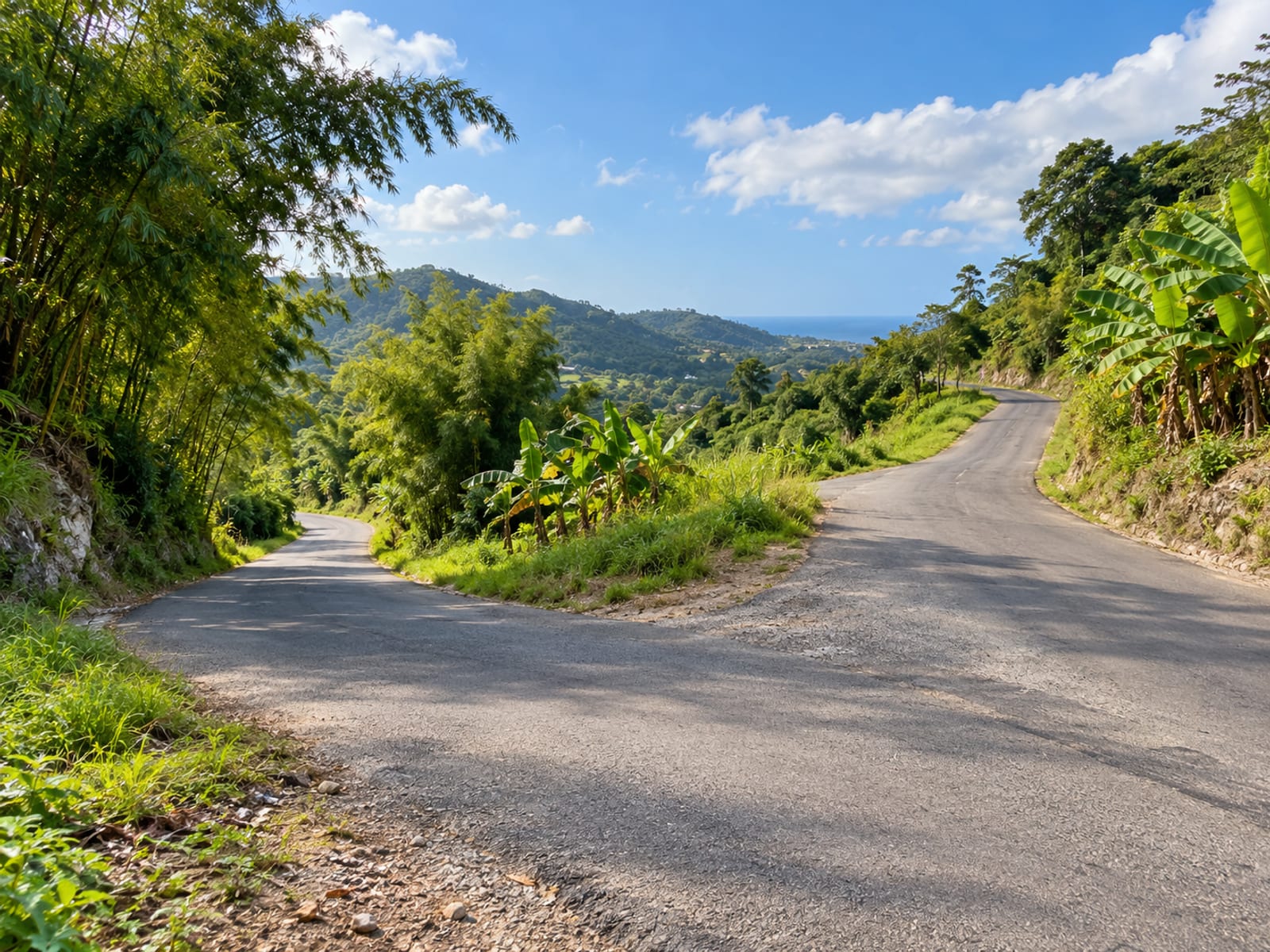 Country road splitting into two paved branches at a junction between green hills, no vehicles