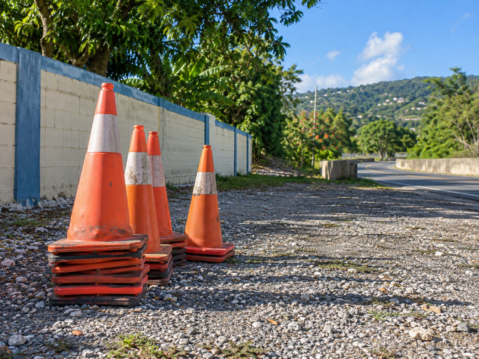 Empty gravel bay beside a road with orange traffic cones stacked at the edge
