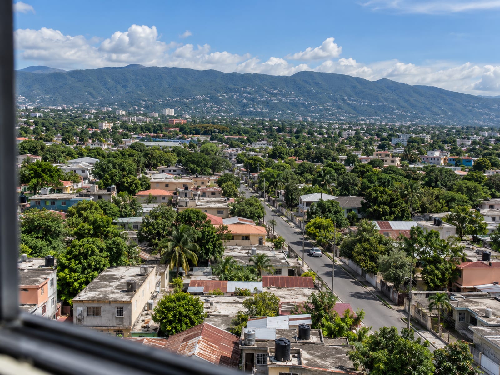 High view across Kingston rooftops with a road winding through and green hills in the distance.