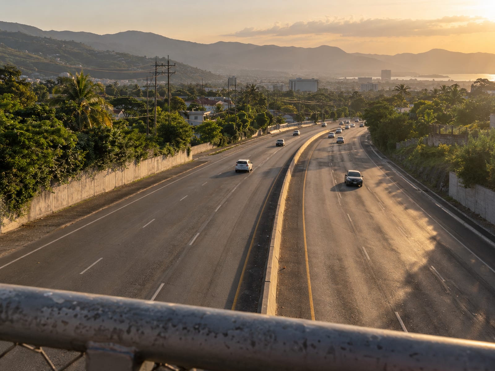 Distant stretch of wide road with a thin line of small plain vehicles and heat haze rising off the asphalt