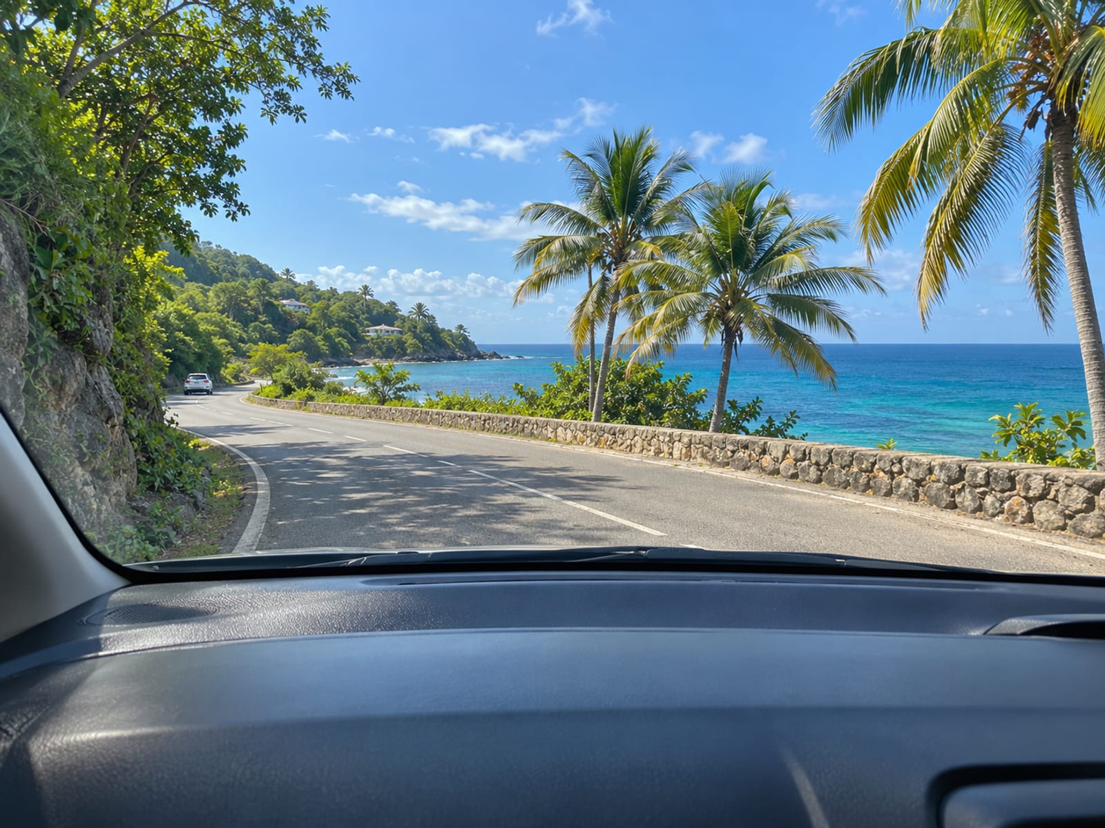 A coastal road seen through a windscreen with the sea ahead