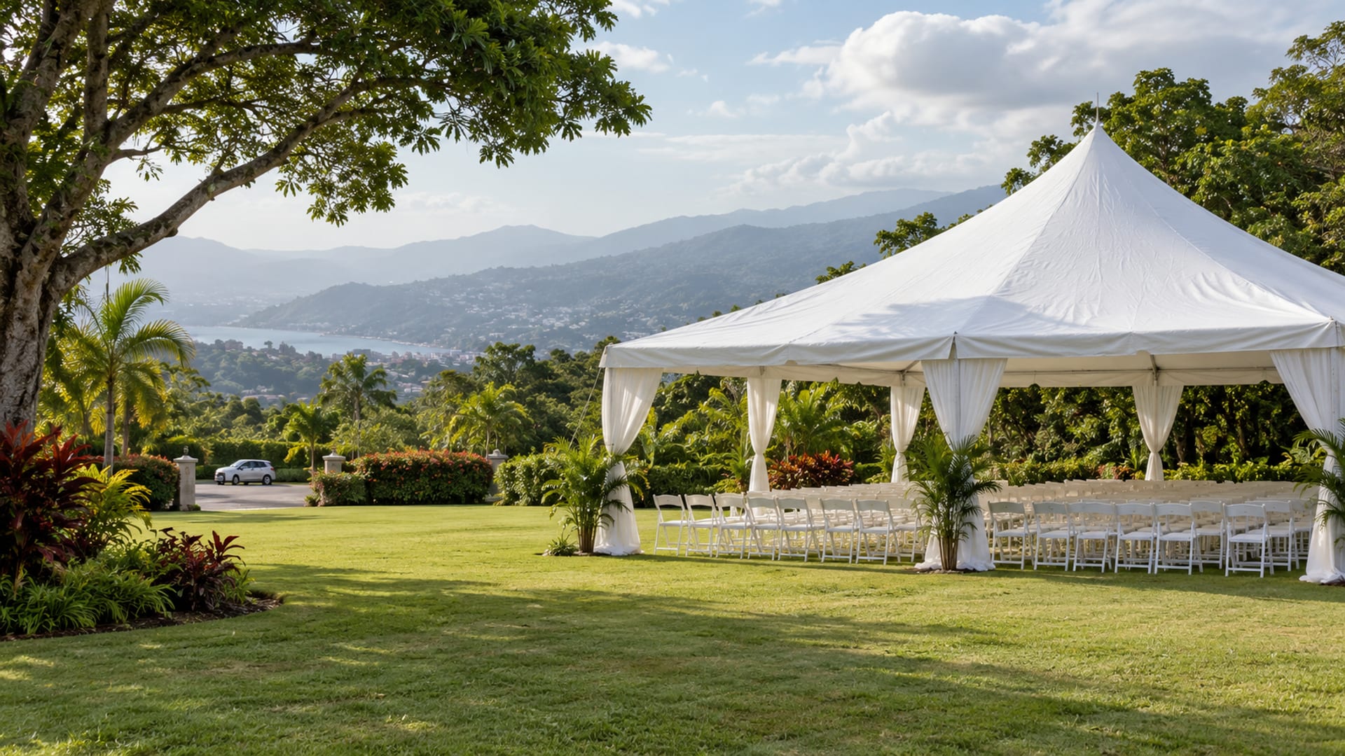 Large empty white tent with rows of unoccupied chairs on a green lawn, hills rising behind
