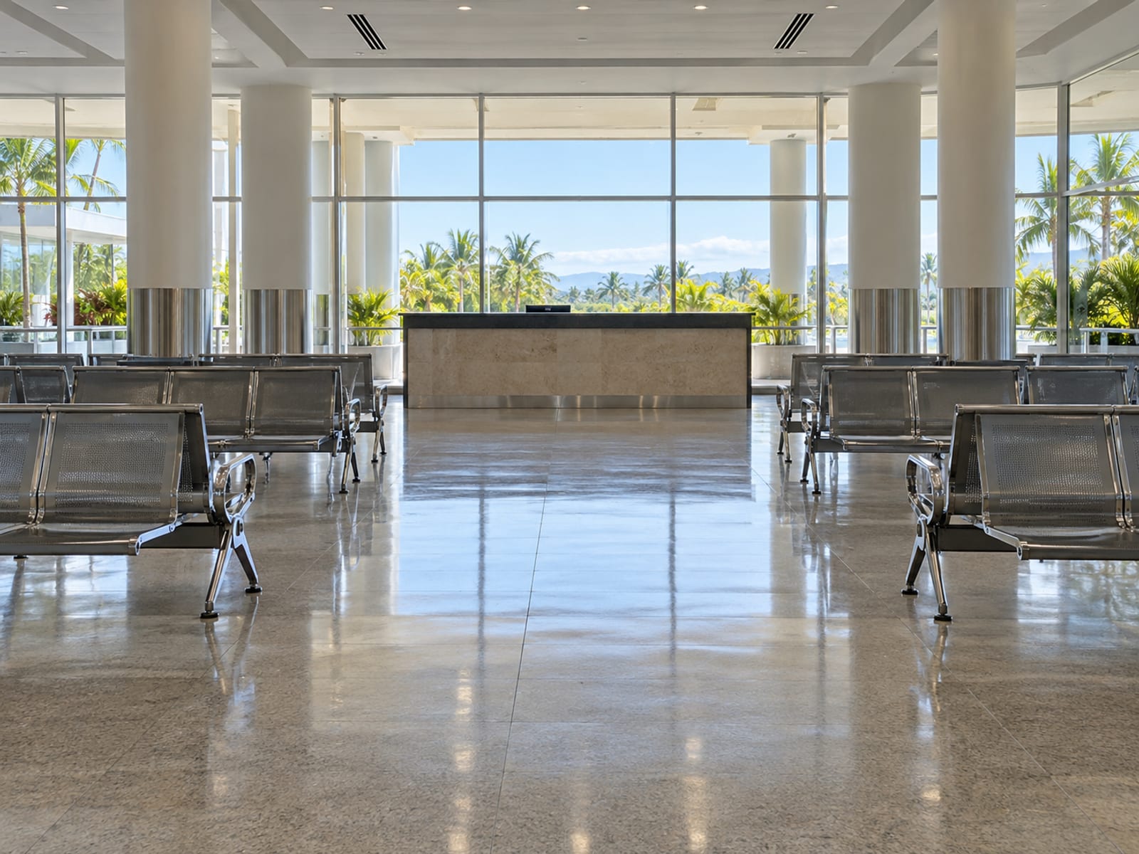 Empty arrivals hall with plain benches and a distant blank desk under daylight