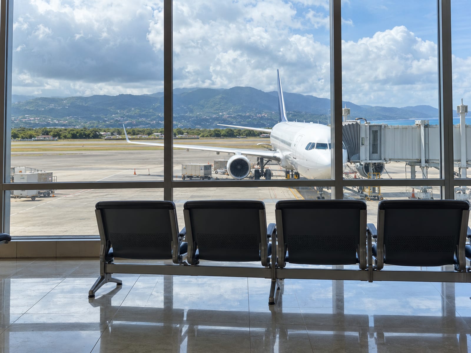 Large window with an aircraft parked on the apron outside and a row of empty seats in the foreground, no text