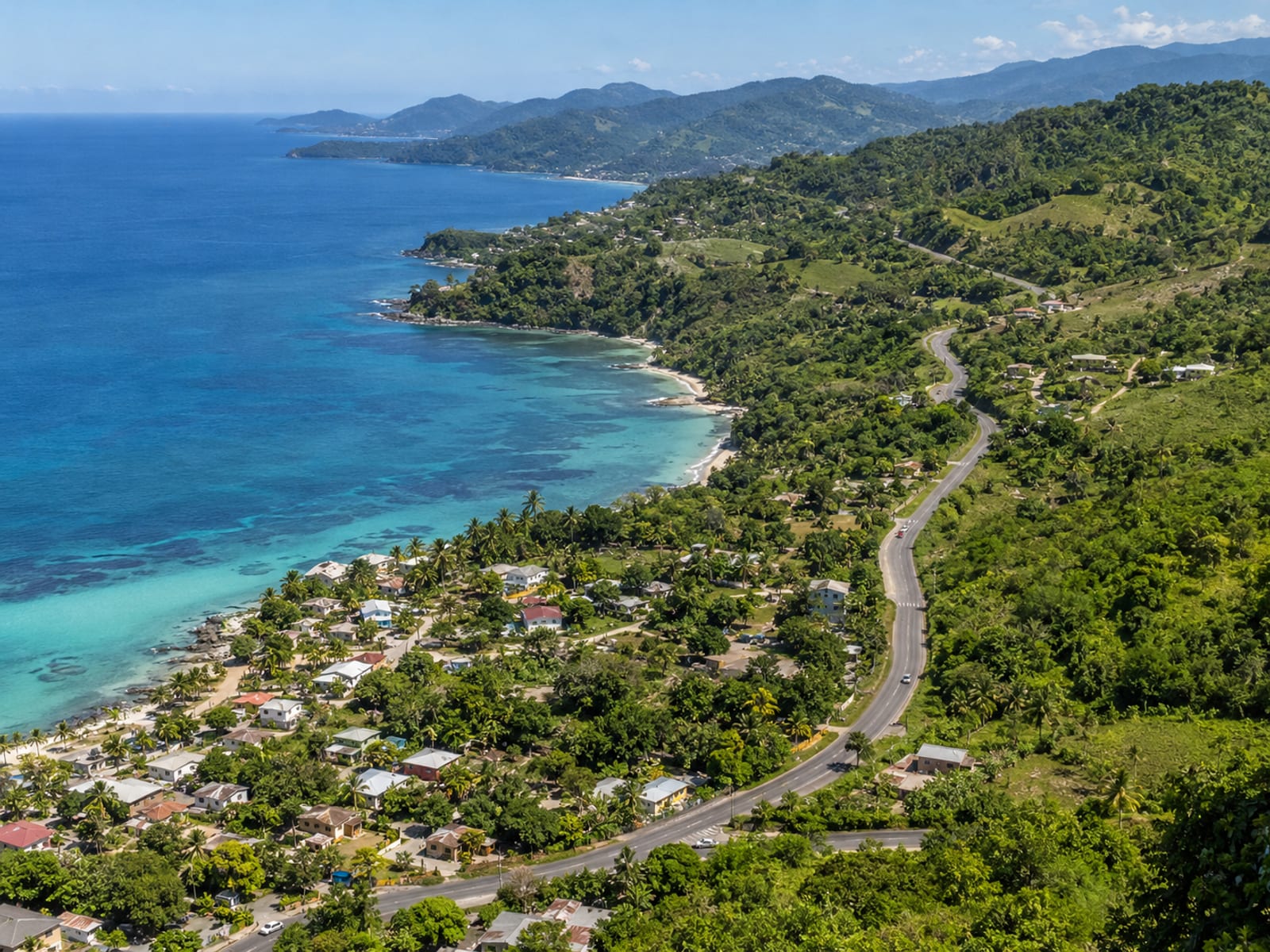 A road winding from a coastal town up into green hills