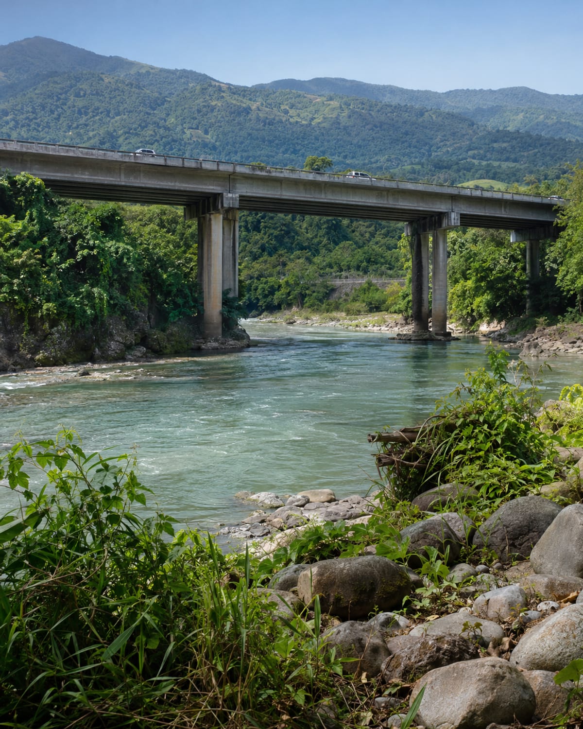 A highway bridge crossing a broad green river valley