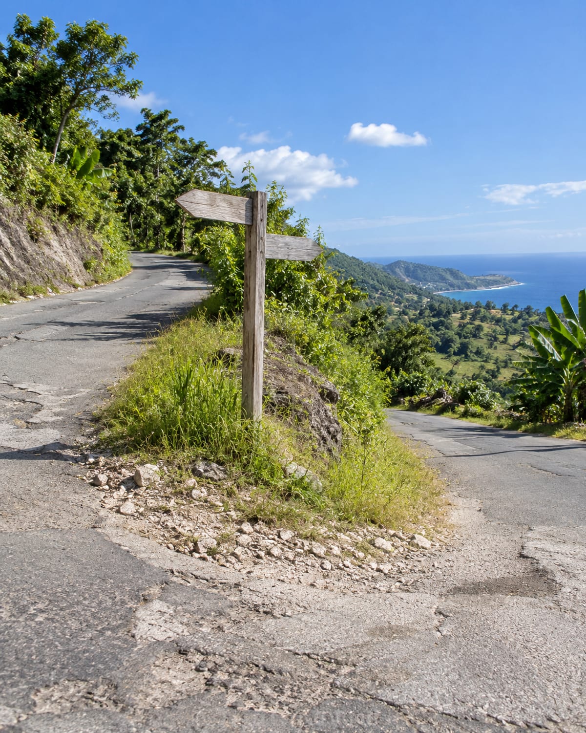 A country road junction with one road climbing into hills and one running toward the coast